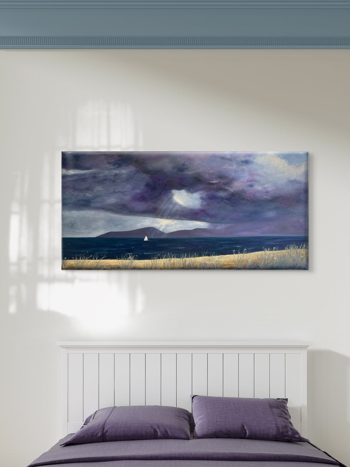 A panoramic original oil on canvas painting of a dramatic purple and blue stormy sky over a dark sea with a sailboat and golden grass, displayed on a white wall above a bed with purple bedding.